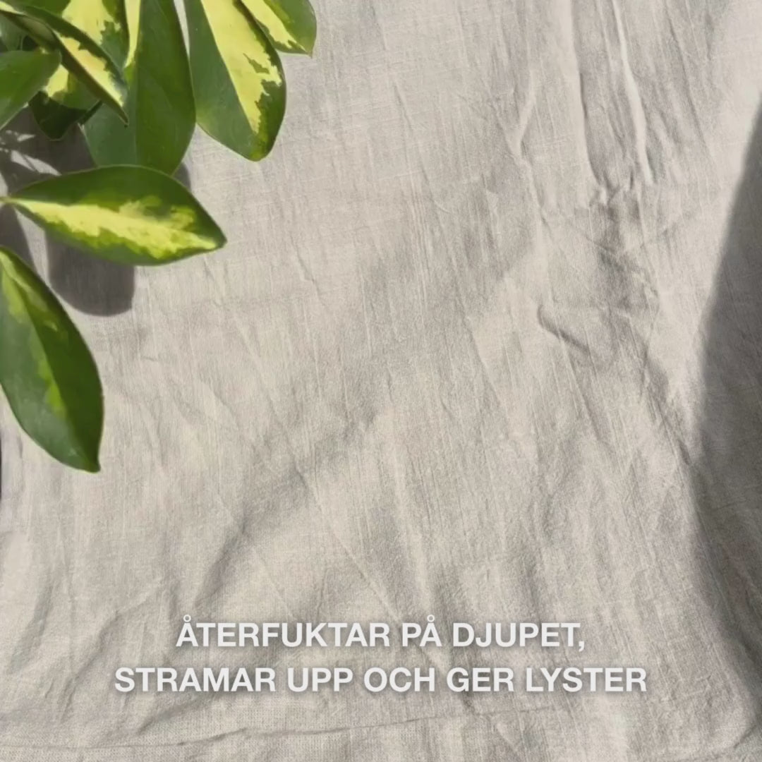 Närbild av en kvinna som applicerar en klarrosa ansiktsmask med vitamin B12 och kollagen på ren hud: hon slätar ut den över kinder, panna och haka, medan kollagen- och B12-berikad formula återfuktar, stärker, lugnar och ger en strålande hud.
