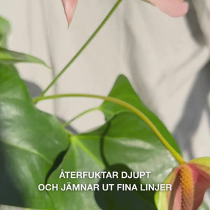 Närbild av en hand som släpper några droppar silkeslen, klar ansiktsserum med pipett på fingertopparna och varsamt masserar in den i lätt fuktad hud – den lätta, snabbt absorberande texturen återfuktar omedelbart, fyller ut fina linjer och lugnar med 2 % hyaluronsyra, vitamin B5 och tea‑tree‑olja 